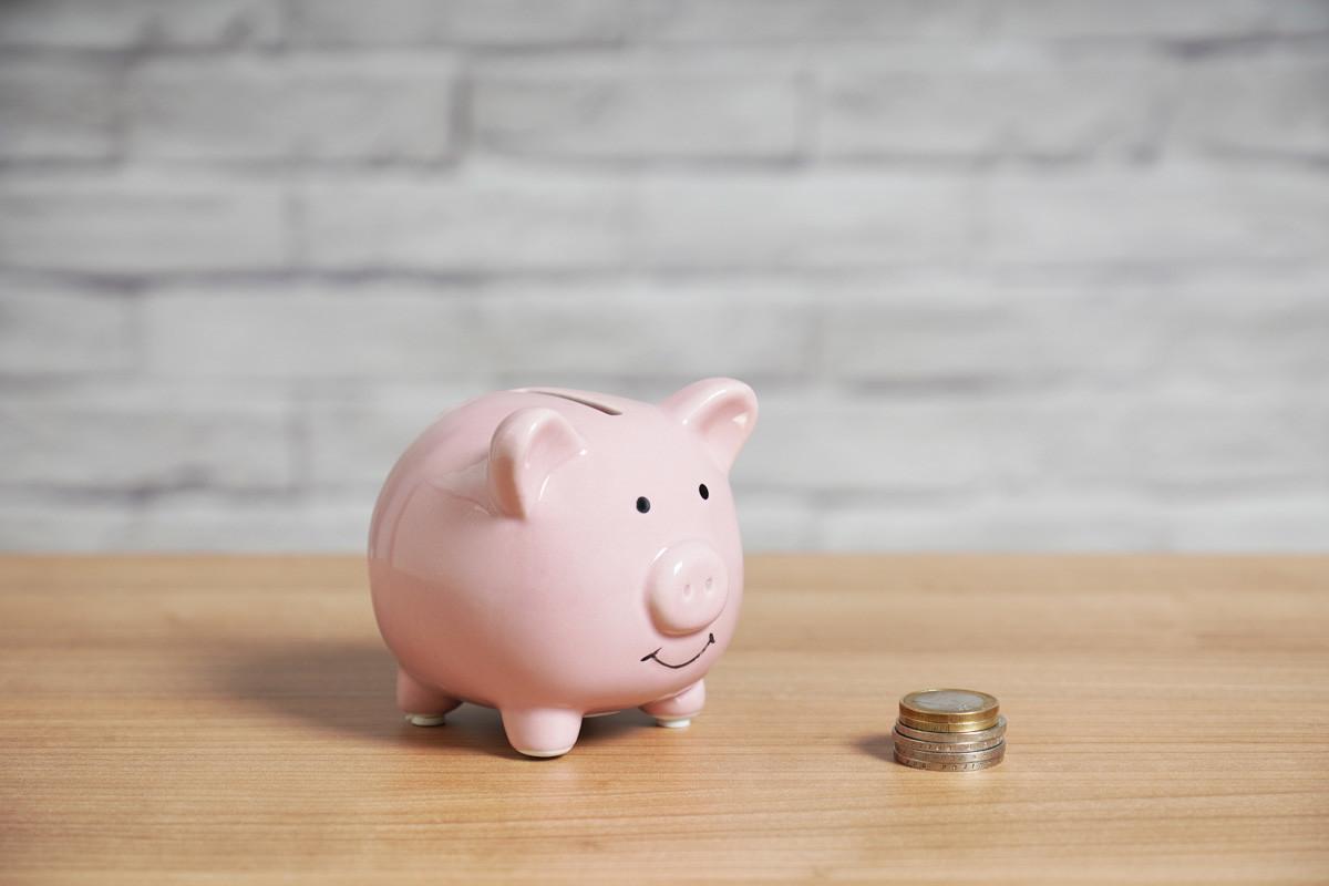 Piggybank with Stack of Euro Coins on Table
