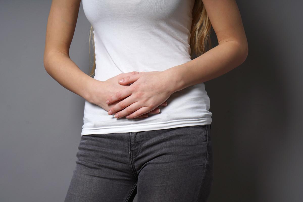 Unrecognizable Young Woman Holding Her Stomach with Both Hands 